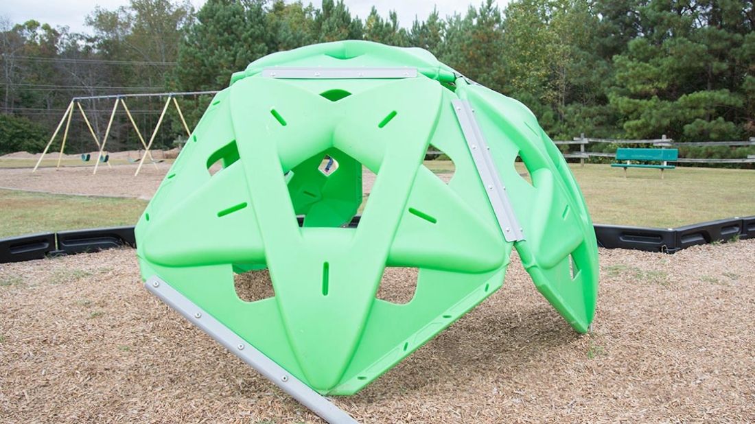 Green climbing dome at Carrollton Elementary School playground with cut-out sections and metal bars for support.